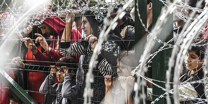 I migranti appoggiato alle inferriate e al filo spinato che proteggono il confine tra Serbia e Ungheria. (ARMEND NIMANI/AFP/Getty Images)