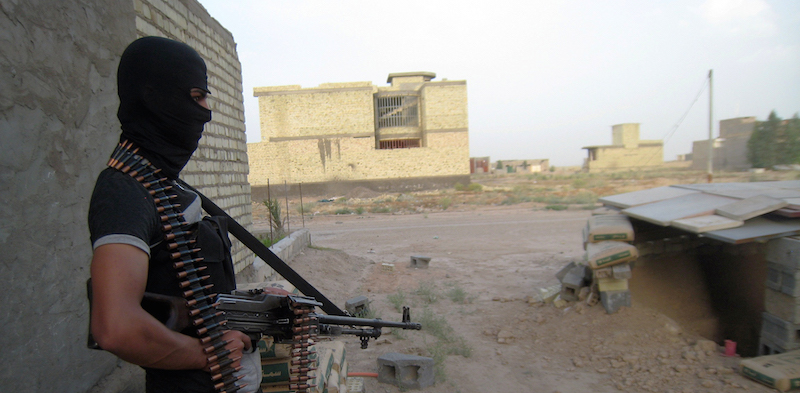 Un uomo mascherato fa la guardia a un edificio di Fallujah, Iraq (AP Photo)