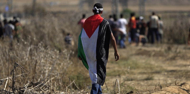 Un ragazzo palestinese avvolto nella bandiera della Palestina manifesta contro gli israealiani vicino al confine israeliano con la Striscia di Gaza, 11 ottobre 2015 (MOHAMMED ABED/AFP/Getty Images)