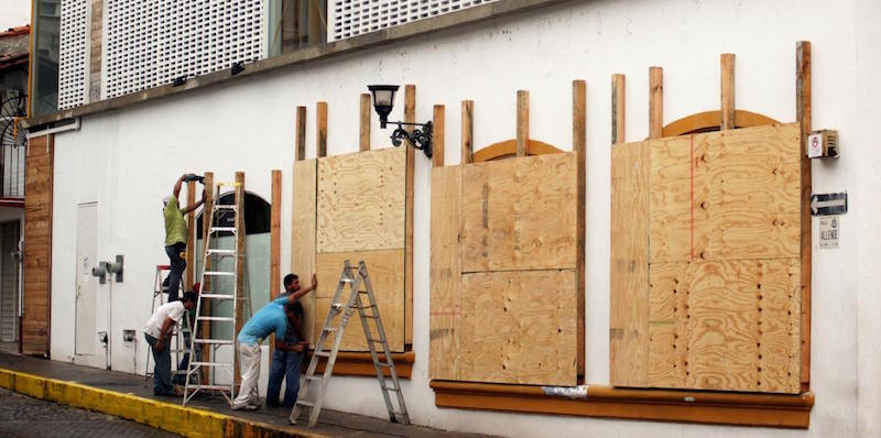 Alcuni uomini mettono delle protezioni sulle vetrine di un negozio a Puerto Vallarta, nello stato messicano di Jalisco, in vista dell'arrivo dell'uragano Patricia. (Xinhua/David Diaz)