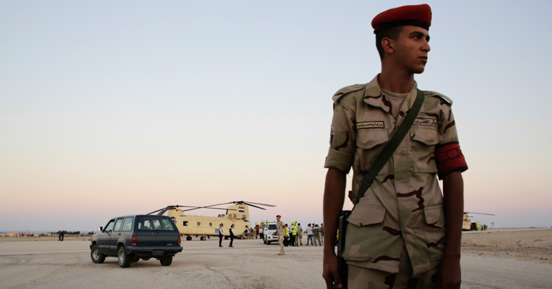 Un soldato egiziano sorveglia il luogo dove alcuni soccorritori stanno scaricando da un elicottero della polizia i cadaveri delle vittime del volo che si è schiantato nel Sinai. (AP Photo/Amr Nabil)