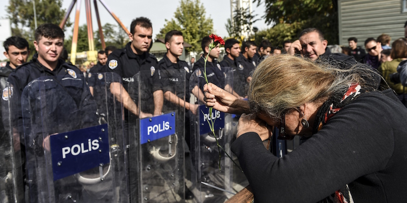 Una donna lascia dei garofani di fronte alla polizia turca ad Ankara, nel luogo dell'attentato di sabato. (BULENT KILIC/AFP/Getty Images)