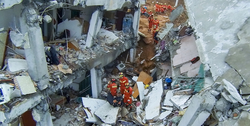 Un gruppo di soccorritori all'interno di una casa parzialmente crollata. (AP Photo/Andy Wong)