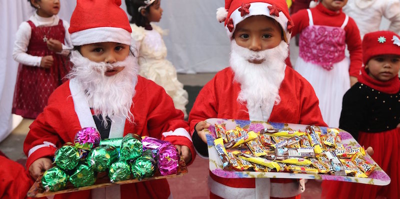 Due bambini vestiti da Babbo Natale offrono dolcetti e regali durante i festeggiamenti per Natale a Kathmandu. 
(Xinhua/Sunil Sharma)