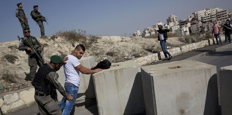 Un poliziotto israeliano perquisisce un ragazzo palestinese nei pressi di un quartiere di Gerusalemme est (AP Photo/Oded Balilty, File)