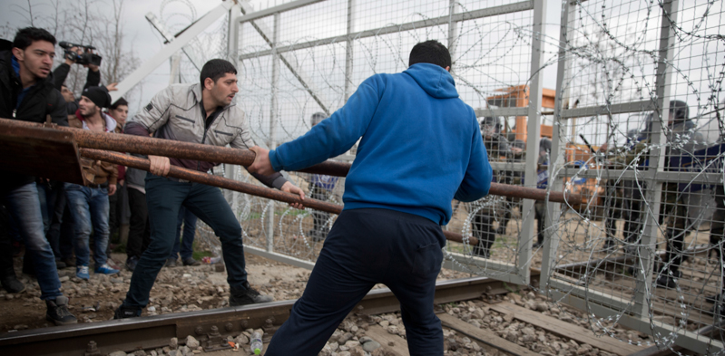 Tre migranti usano un ariete improvvisato per sfondare la barriera tra Grecia e Macedonia. Refugees and Migrant(AP Photo/Petros Giannakouris)