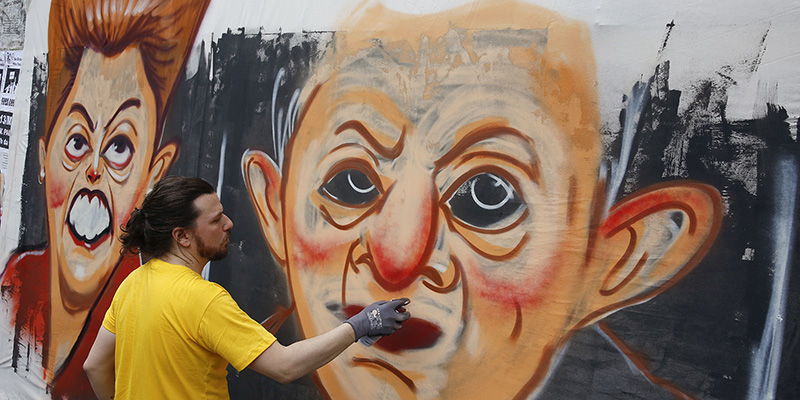 Un artista di strada durante le proteste anti-governative disegna le caricature di Luiz Inacio Lula da Silva e dell'attuale presidente del paese Dilma Rousseff, San Paolo, 13 marzo 2016 (AP Photo/Andre Penner)