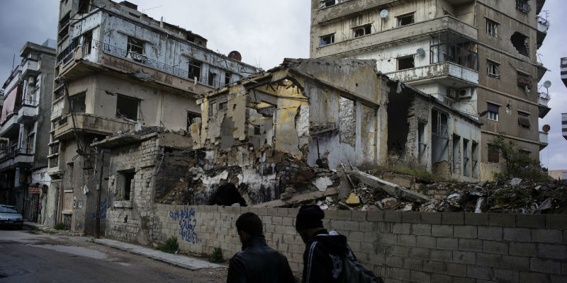 Due persone camminano vicino a degli edifici distrutti a Hamidiya, il quartiere cristiano di Homs (Lorenzo Tugnoli/For The Washington Post)