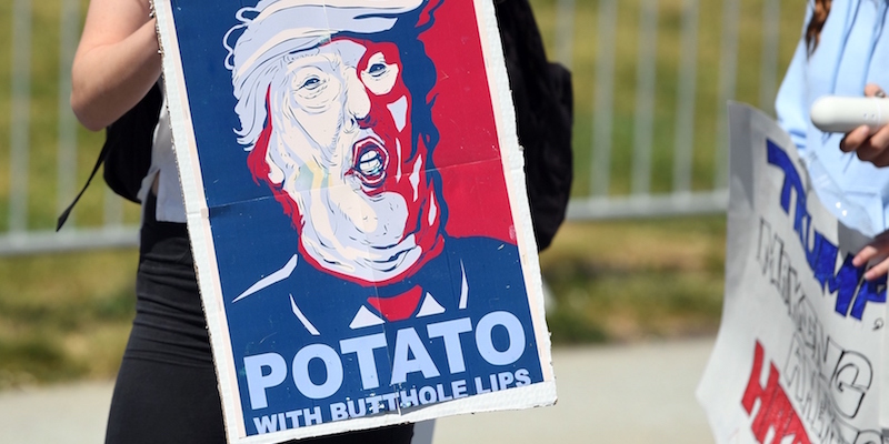 Un finto manifesto elettorale di Trump con scritto Potato with butthole lips ("una patata con la bocca a culo di gallina") viene esposta da una manifestante fuori dalla convention del partito Repubblicano di Burlingame, California, 29 aprile 2016 (JOSH EDELSON/AFP/Getty Images)