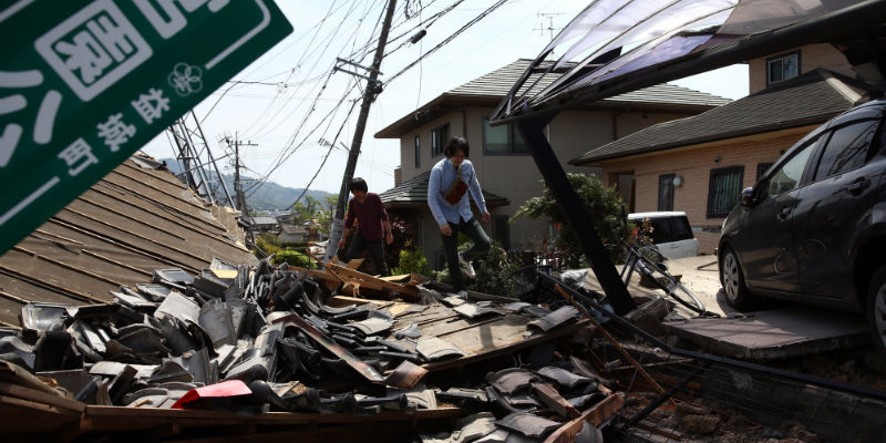 Due uomini sulle macerie di una casa a Mashiki, un'area colpita dal terremoto vicino a Kumamoto, il 20 aprile 2016 (Carl Court/Getty Images)