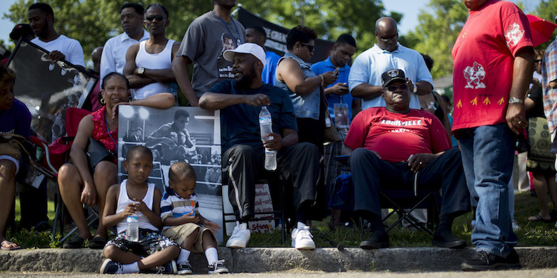 Un gruppo di persone sedute sul ciglio della strada della vecchia casa di Muhammad Ali, in attesa del corteo funebre (JIM WATSON/AFP/Getty Images)