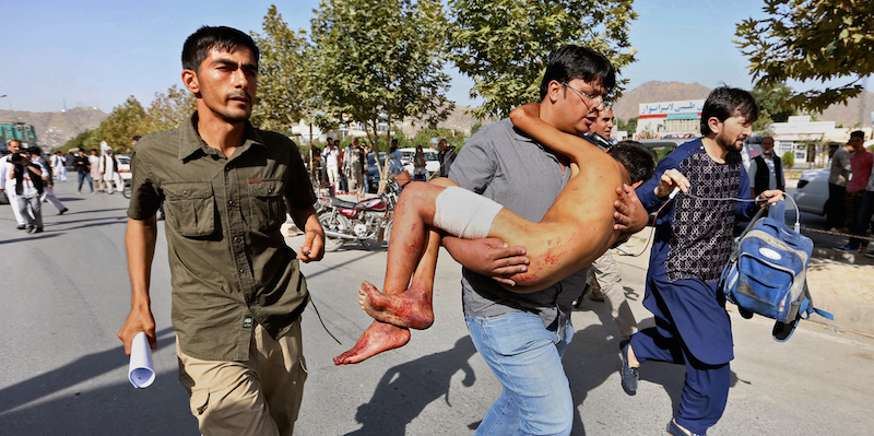 Un uomo porta via un ragazzino ferito durante l'esplosione a Kabul, il 23 luglio 2016 (AP Photo/Rahmat Gul)
