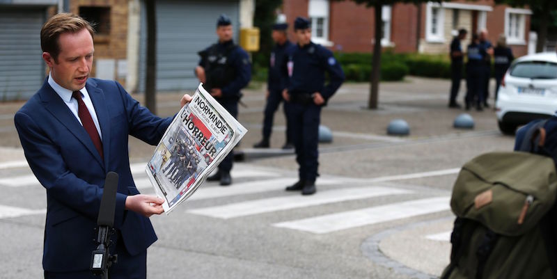 Un giornalista di BBC tiene in mano un giornale che titola in prima pagina "L'orrore", riferito all'attentato nella chiesa di Saint-Étienne-du-Rouvray, in Francia (CHARLY TRIBALLEAU/AFP/Getty Images)