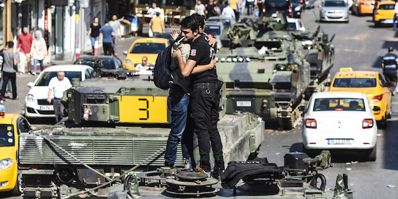 Un agente di polizia turco abbraccia un uomo su un carroarmato usato in precedenza dai golpisti per prendere il controllo di un quartiere di Istanbul, il 16 luglio 2016 (BULENT KILIC/AFP/Getty Images)