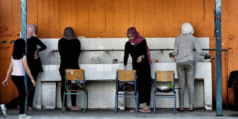 Quattro donne lavano i piatti in una scuola abbandonata usata come rifugio per i richiedenti asilo ad Atene, l'1 luglio 2016 (ARIS MESSINIS/AFP/Getty Images)