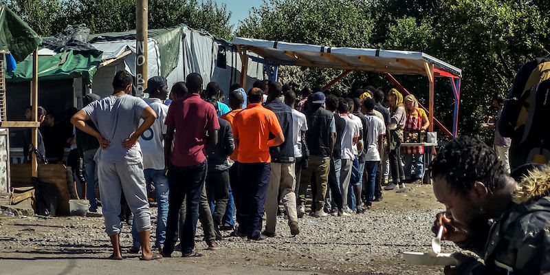 Migranti in fila per ricevere del cibo nel campo profughi di Calais, nel nord della Francia, il 12 agosto 2016 (PHILIPPE HUGUEN/AFP/Getty Images)