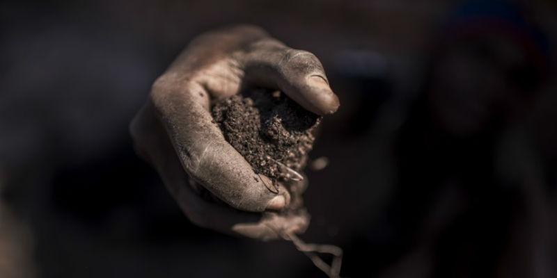 Un uomo con della terra contenente cobalto al mercato dei minerali di Musompo, in Congo (Michael Robinson Chavez/The Washington Post)