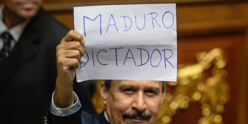 Un deputato venezuelano tiene in mano un foglio su cui si legge "Maduro dittatore" in parlamento, a Caracas, il 23 ottobre 2016 (FEDERICO PARRA/AFP/Getty Images)