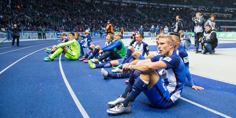 I giocatori dell'Hertha Berlino seduti davanti ai propri tifosi dopo la vittoria contro il Colonia (ODD ANDERSEN/AFP/Getty Images)