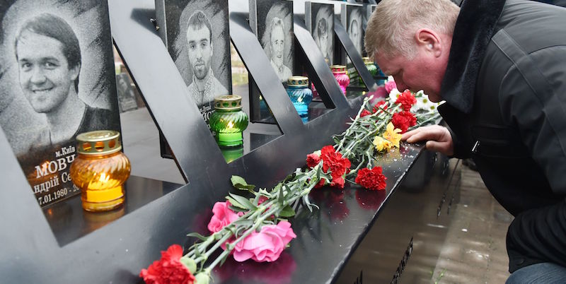 Un uomo inginocchiato rende omaggio al monumento ai morti di Piazza Indipendenza a Kiev, nel terzo anniversario dall'inizio degli scontri il 21 novembre 2013 (Photo credit should read SERGEI SUPINSKY/AFP/Getty Images)