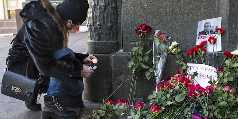 Una donna accende una candela di fronte a una fotografia di Andrei Karlov, fuori dal ministero degli Esteri a Mosca (AP Photo/Alexander Zemlianichenko)