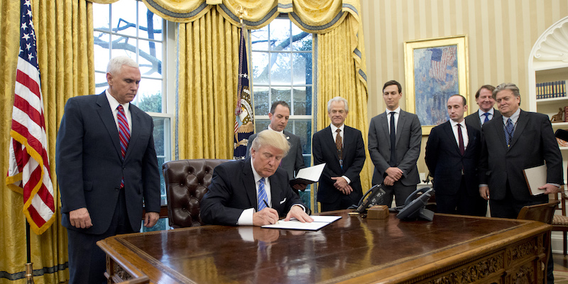 Il presidente degli Stati Uniti Donald Trump firma uno dei suoi tre primi ordini esecutivi nello Studio Ovale, il 23 gennaio 2017 (Ron Sachs - Pool/Getty Images)