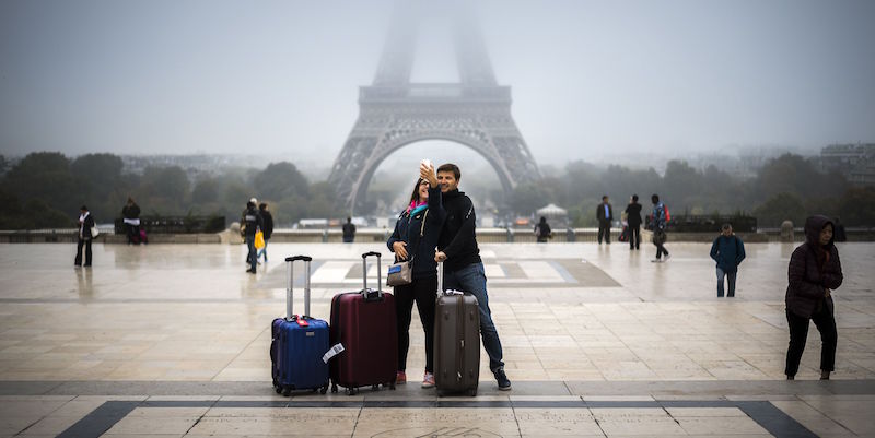 Due turisti mentre fanno un selfie di fronte alla Tour Eiffel di Parigi (LIONEL BONAVENTURE/AFP/Getty Images)