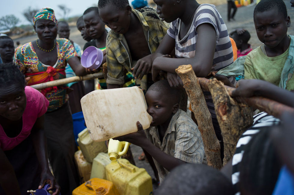 Un bambino fra un gruppo di richiedenti asilo beve dell’acqua in un accampamento per profughi. Da tre anni a questa parte circa 1,5 milioni di richiedenti asilo sono arrivati in Uganda, prevalentemente dal Sud Sudan (Dan Kitwood/Getty Images)

