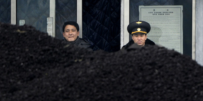 Un militare e un civile nordcoreani vicini a un cumulo di carbone a Siniuju, una città al confine con la Cina, nel 2012 (WANG ZHAO/AFP/Getty Images)