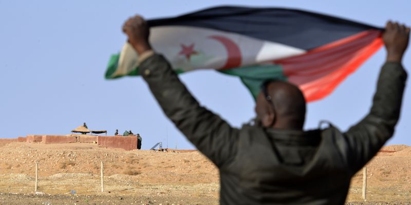 Un uomo di etnia Saharawi con una bandiera del Fronte Polisario di fronte alla barriera interna del Sahara Occidentale, presidiata da soldati marocchini, nell'area di al Mahbes, il 3 febbraio 2017 (STRINGER/AFP/Getty Images)