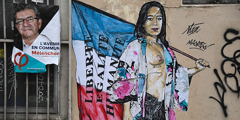 Un murale a Parigi accanto a un manifesto elettorale di Jean-Luc Mélenchon, 18 marzo 2017 (BERTRAND GUAY/AFP/Getty Images)