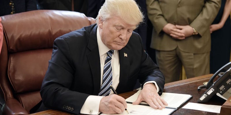 Il presidente degli Stati Uniti Donald Trump mentre firma degli atti nello Studio Ovale
(Olivier Douliery - Pool/Getty Images)