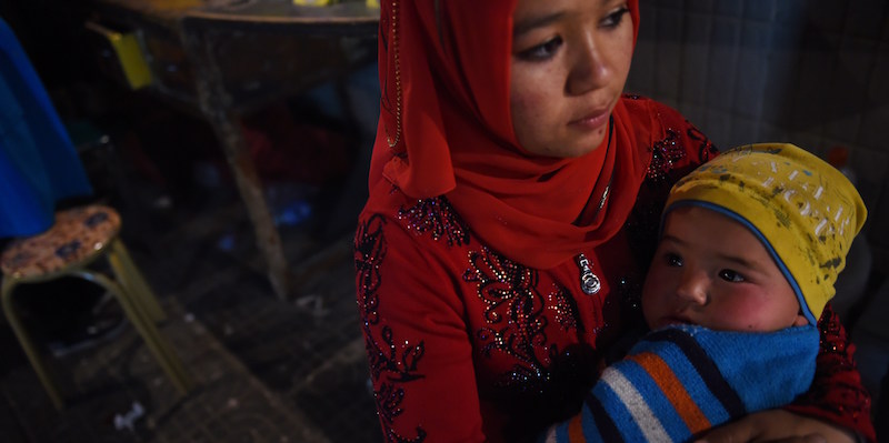 Una donna uiguri con in braccio un bambino in un mercato di Hotan, nella provincia dello Xinjiang, in Cina
(GREG BAKER/AFP/Getty Images)