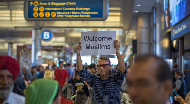 Un attivista mostra un cartello di benvenuto per i musulmani nell'area arrivi dell'aeroporto internazionale di Los Angeles, California (David McNew/Getty Images)