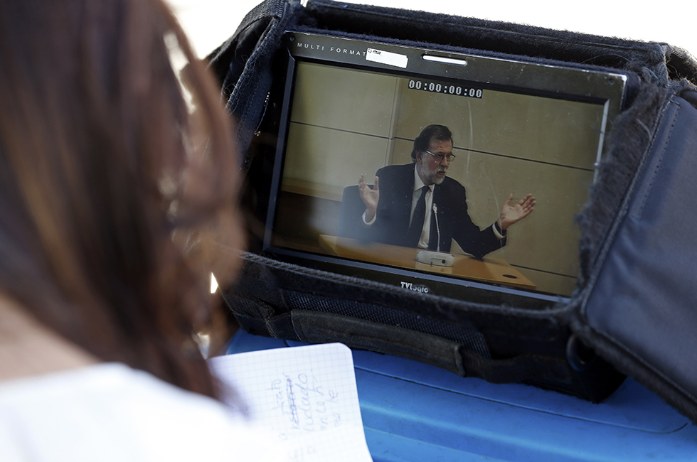 Un monitor fuori dal tribunale in cui si vede il primo ministro spagnolo Mariano Rajoy mentre testimonia davanti ai giudici, 26 luglio 2017 (AP Photo/Francisco Seco)