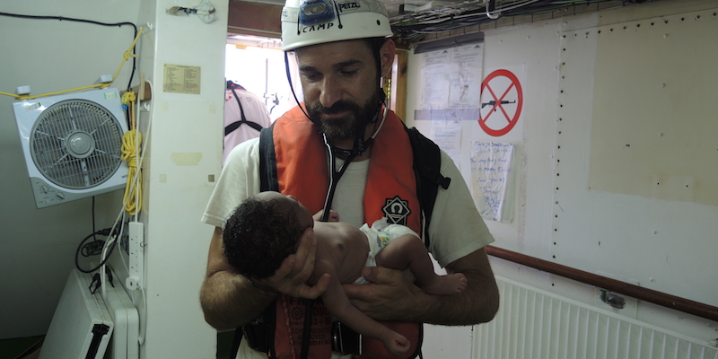 Craig Spencer, un medico di Medici Senza Frontiere, tiene in braccio un neonato sulla nave Aquarius, il 27 giugno 2017 (Lena Klimkeit/picture-alliance/dpa/AP Images)