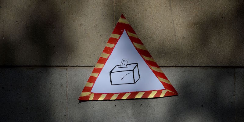Un poster mostra un segnale di pericolo con dentro un seggio elettorale all'Università di Barcellona (JOSEP LAGO/AFP/Getty Images)