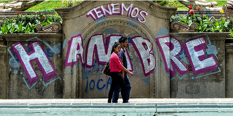Una coppia passeggia davanti alla scritta "Abbiamo fame" a Caracas, agosto 2017
(RONALDO SCHEMIDT/AFP/Getty Images)