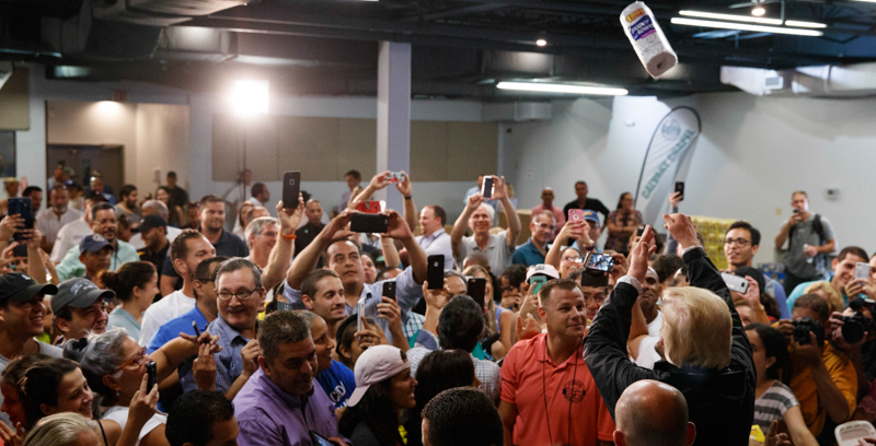 Il presidente degli Stati Uniti Donald Trump lancia della carta assorbente sulle persone che si sono riunite per vederlo a Porto Rico. (AP Photo/Evan Vucci)