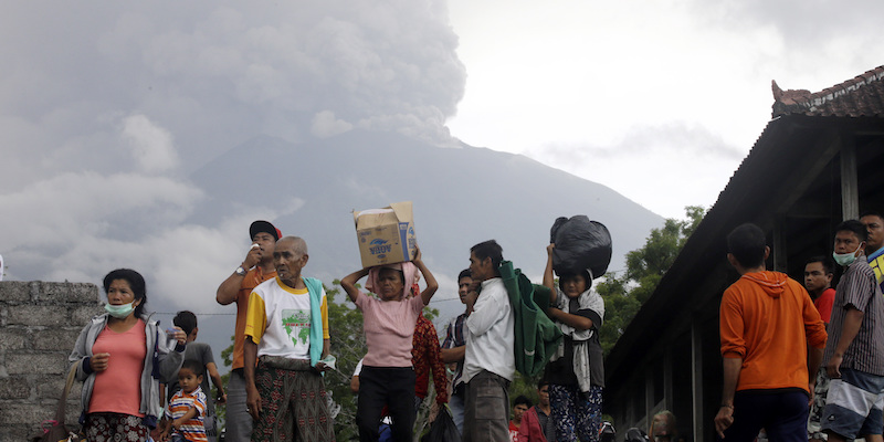 Un gruppo di abitanti di Karangasem, sull'isola di Bali, lasciano le loro case per fuggire dall'eruzione del vulcano Agung, che si vede sullo sfondo, il 26 novembre 2017 (AP Photo/Firdia Lisnawati