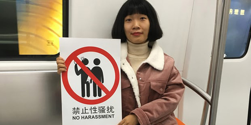 Zheng Xi con un cartello contro le molestie sessuali. 