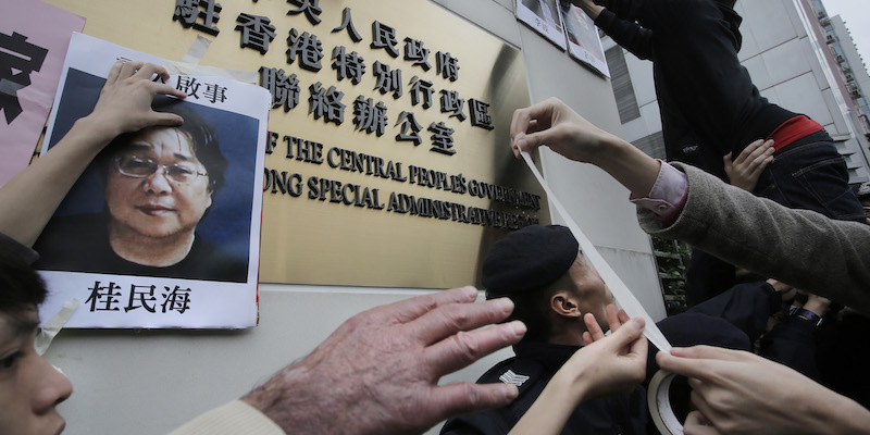 Manifestanti attaccano dei volantini con la faccia del libraio ed editore Gui Minhai fuori da un edificio governativo cinese a Hong Kong, il 3 gennaio 2016 (AP Photo/Vincent Yu,File)