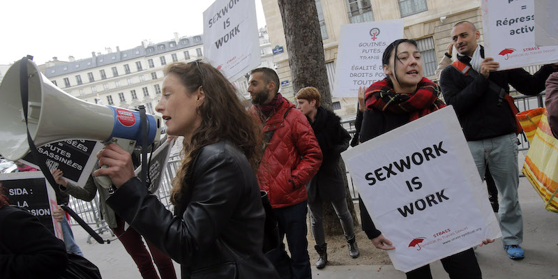 Lavoratori del sesso francesi protestano di fronte all'Assemblea Nazionale a Parigi, il 17 settembre 2013; sul cartello in inglese c'è scritto «Il lavoro di chi si prostituisce è lavoro», uno degli slogan principali dei movimenti di difesa dei diritti di chi si prostituisce per scelta (AP Photo/Christophe Ena)