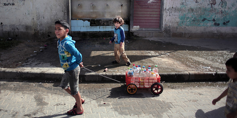 Due bambini palestinesi che trasportano dei vuoti di bottiglia, Gaza, 16 aprile 2016 
AP Photo/Khalil Hamra)