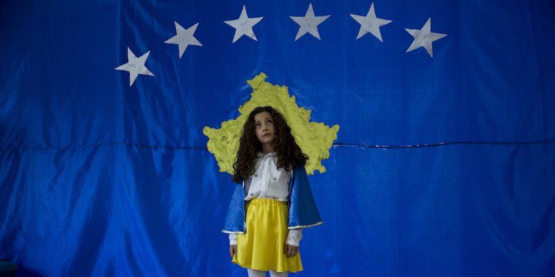 Pavaresia Sopi, considerata la prima bambina a essere nata nel Kosovo indipendente, posa per una foto di fronte alla bandiera del suo paese nella scuola di Sllovi, in Kosovo, il 16 febbraio 2018; "pavaresia" significa "indipendenza" (AP Photo/Visar Kryeziu)