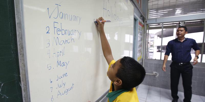 Uno scolaro scrive i nomi dei mesi in inglese in una scuola primaria di Bangkok, in Thailandia, il 2 marzo 2015 (ANSA/EPA/BARBARA WALTON)
