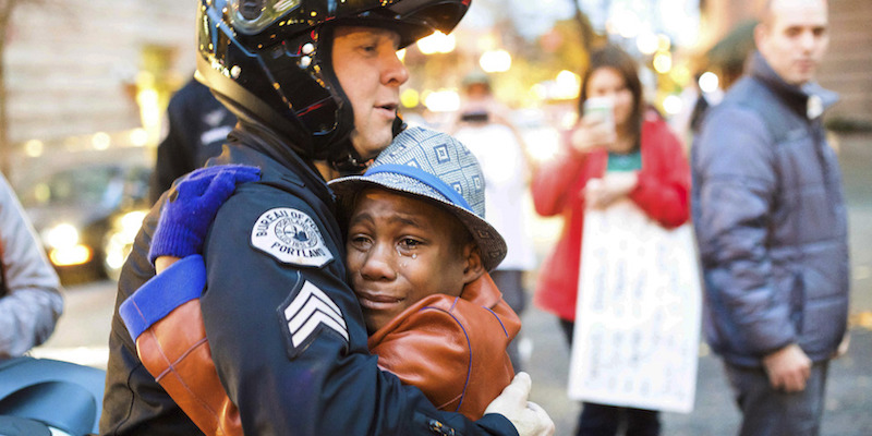 Devonte Hart nella famosa fotografia in cui abbraccia il sergente Bret Barnum, il 25 novembre 2014, a Portland, in Oregon (Johnny Huu Nguyen via AP, File)