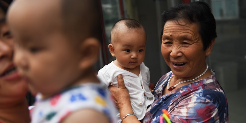 Una donna anziana con un bambino in braccio a Pechino, il primo agosto 2017 (GREG BAKER/AFP/Getty Images)