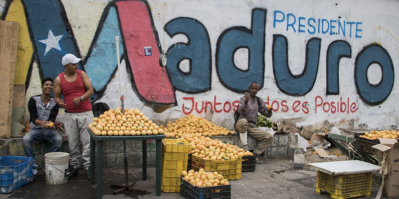 24 April 2018, Venezuela, Caracas: Three men selling fruit before a wall with political propaganda for President Maduro. Maduro is seeking another term in office in the elections taking place on 20 May. However, numerous countries and international organisations fear that the elections will be neither free nor fair. Photo by: Rayner Pena/picture-alliance/dpa/AP Images