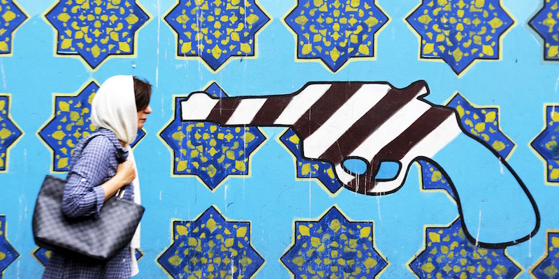 Una donna iraniana di fronte a un murale disegnato fuori dall'ex ambasciata americana a Teheran (ATTA KENARE/AFP/Getty Images)